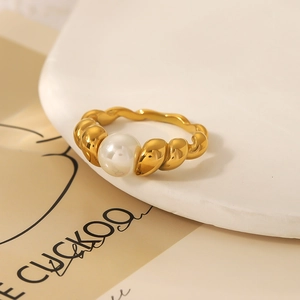 Detailed view of a gold-tone twisted croissant ring featuring a central white pearl