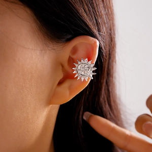 Macro shot of silver sun-face ear cuff clip on a model showing metallic sunburst detail