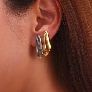Close-up of irregular lava style gold earrings worn by a model in a minimalist style