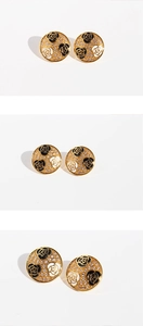 Macro shot of circular gold earrings with camellia flowers and sparkling zircon micro-pave