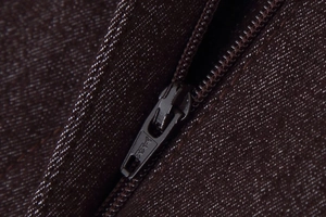 Vue détaillée de la fermeture éclair YKK en métal sur le pantalon marron à surpiqûres