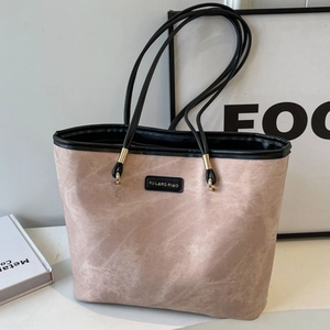 Minimalist beige tote bag with black handles and gold hardware on a clean desk