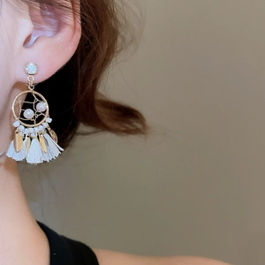 Macro shot of bohemian fringe earrings with gold finish, pearls and leaf charms on model