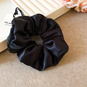 Détail d'un chouchou en satin noir fait main avec finition brillante et texture plissée