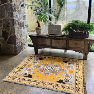 Close-up of bohemian style woven blanket featuring yellow floral patterns and fringe details