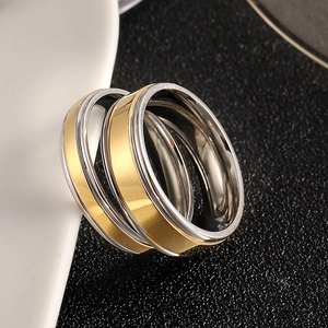 Close-up of dual-tone silver and gold stainless steel ring on textured background