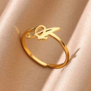 Adjustable golden stainless steel ring with elegant cursive initial on satin background