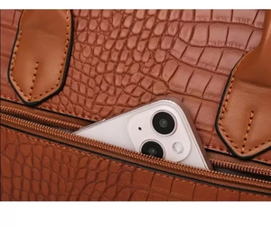 Detail of brown crocodile pattern handbag showing a back zipper pocket with a smartphone