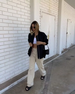 Street style shot of a woman in a black bomber jacket, beige cargo pants, and white crop top