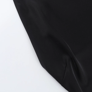 Detail view of the smooth black satin fabric and glossy texture on the fitted dress