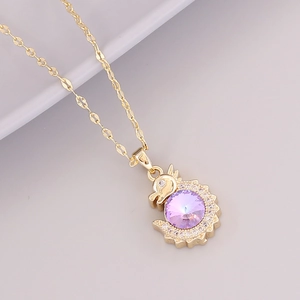 Close-up of golden dragon pendant with a large purple gemstone and sparkling zircon halo