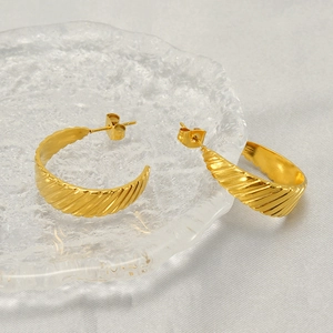 Classic gold titanium steel U-shaped spiral textured hoop earrings on a glass plate