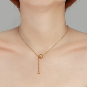 Gros plan d'un collier en Y plaqué or 18 carats avec perles en métal sur un mannequin
