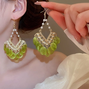 Detail of chandelier earrings with pearls and lime green shell tassels for vacation