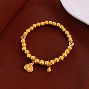 Detail of beaded bracelet with matte gold coins, Buddha head and lotus charm on silk