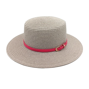 Detail of woven straw sun hat texture with vibrant fuchsia leather band and gold buckle