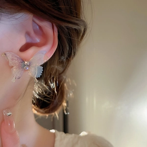 Détail de la boucle d'oreille papillon avec ailes dégradées et cristaux brillants