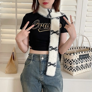 Close-up of white plush scarf with black bow patterns on a stylish model