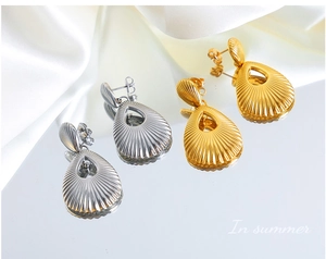 Detail of teardrop hollow 18K gold and silver titanium earrings on white silk fabric
