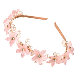 Close-up of pink matte flowers and white pearls on a gold floral headband for women