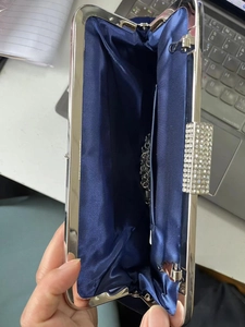 Detail of dark blue satin evening clutch featuring rhinestone clasp and silver chain strap