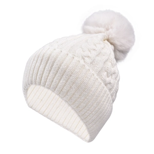 Close-up of cream knit beanie featuring thick cable texture and plush faux fur pom-pom