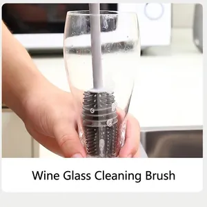Grey silicone cup brush with long handle cleaning a transparent glass in a kitchen