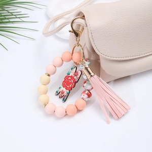 Silicone bead keychain wristlet with pink tassel and floral charm on a handbag