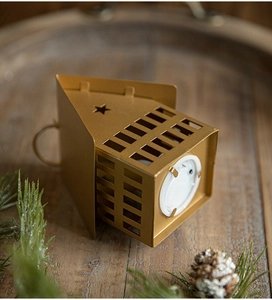 Golden metal house candle holder with LED light, pine needles and cones on wood base