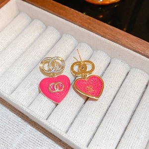 Close-up of gold-plated heart earrings with pink enamel and sparkling zircon detail