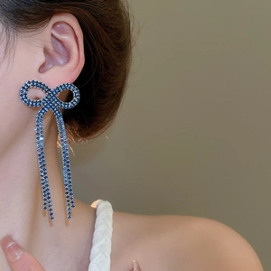 Detail view of dark blue bow tassel earrings with sparkling rhinestones on model