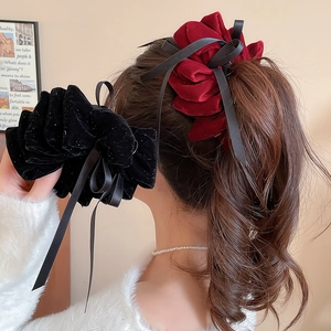 Détail de pinces à cheveux élégantes en velours avec longs rubans noir et rouge vin