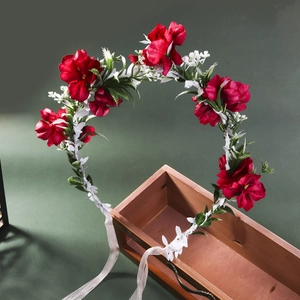 Handmade floral crown with red and white roses and ribbon on a rustic wooden box