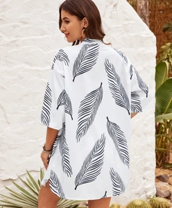 Rear view of white longline cardigan with black leaf print against white textured wall