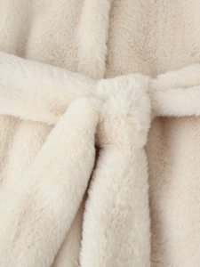 Detail of belted waist on faux fur cream coat showing plush texture and soft material
