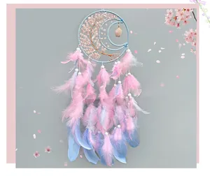 Detail of pink crystal dreamcatcher with moon frame and feathers on floral background