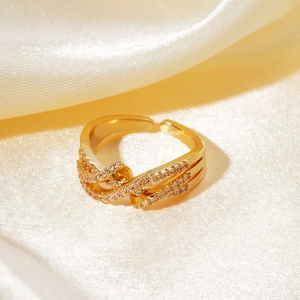 Close-up of triple-layered gold ring with micro-pave zircons on beige silk background