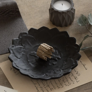 Detail van matzwarte lotus harsschotel met houten ring en minimalistische kaars decor