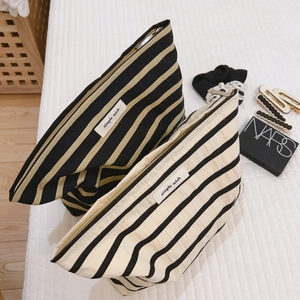 Striped cotton canvas makeup bags in black and cream on white quilted bedding background