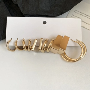 Detailed flat lay of golden C-shape geometric earring set on white and black texture