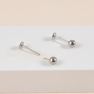 Polished stainless steel T-shape labret studs and ball replacement on a white block