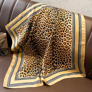 Fashionable leopard print satin silk square scarf on brown leather with sunglasses