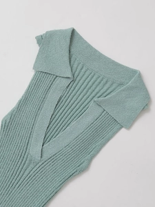 Detail van een mintgroene mouwloze gebreide jurk met V-hals en een polo kraag