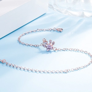 Detailed view of a rose gold cat paw bracelet with heart-shaped purple stone and crystals