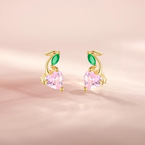 Detailed close-up of pink heart-shaped cherry earrings with green leaf gemstones