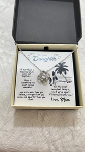 Close-up of silver necklace with knot pendant and greeting card in jewelry box