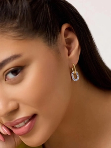 Close-up of 18K gold U-shaped earrings with blue and white enamel floral pattern pendants