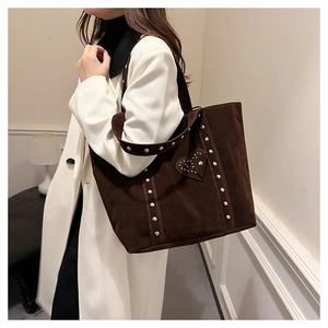 Detail of dark brown suede tote bag with heart patch and rivets on shoulder strap