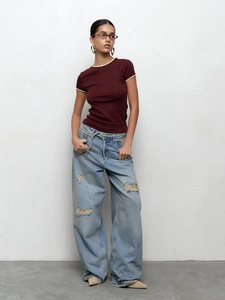Gros plan sur la maille du t-shirt à col rond contrasté et les détails du jean déchiré