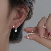 Close-up of woman wearing silver star earrings with a U-shaped minimalist metal hook